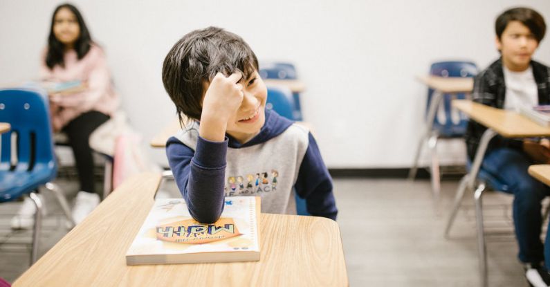 Cyberbullying Prevention - Boy Smiling While Sitting on His Desk
