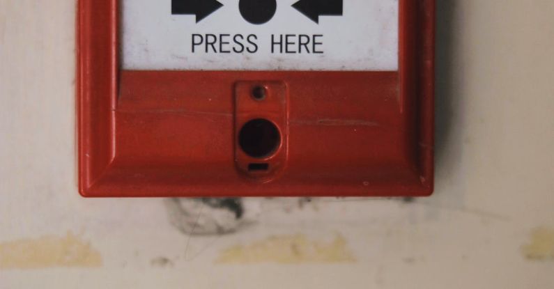 Spyware Detection - Manual emergency red fire alarm system box with push button placed on white shabby wall in light room of building