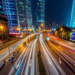 Smart City - Timelapse Photography of Vehicle on Concrete Road Near in High Rise Building during Nighttime